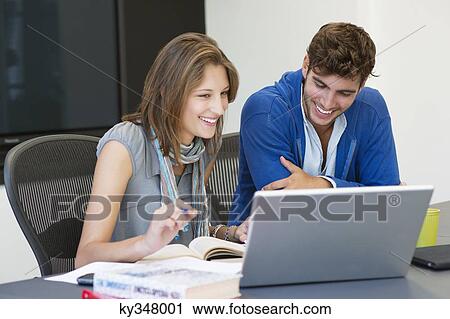 University students smiling while using laptop in classroom View Large Photo Image Stock Image - University students smiling while using laptop in classroom. Fotosearch