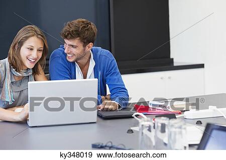 University students smiling while using laptop in classroom View Large Photo Image Stock Photo - University students smiling while using laptop in classroom. Fotosearch