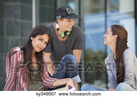 Portrait of a woman sitting with her friends looking at each other View Large Photo Image Stock Photo - Portrait of a woman sitting with her friends looking at each other. Fotosearch