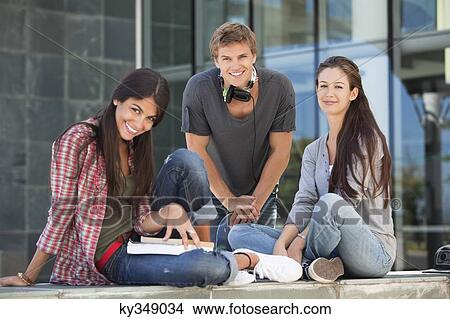 Picture - Portrait of smiling young students sitting in campus. Fotosearch