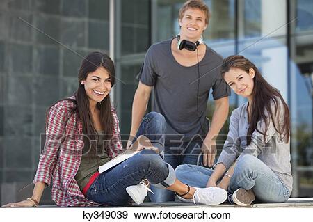 Smiling young students sitting in campus View Large Photo Image Stock Photo - Smiling young students sitting in campus. Fotosearch