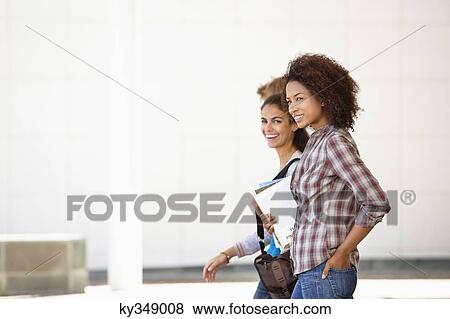 Stock Photo - Two female friends walking in campus. Fotosearch