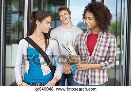 Two women looking at each other with their friend laughing in the background View Large Photo Image Stock Photo - Two women looking at each other with their friend laughing in the background. Fotosearch