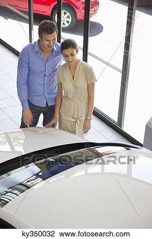 Couple looking at a car at a showroom View Large Photo Image Stock Image - Couple looking at a car at a showroom. Fotosearch