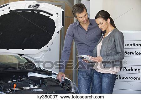 Couple looking at a car catalog in showroom View Large Photo Image Stock Photo - Couple looking at a car catalog in showroom. Fotosearch