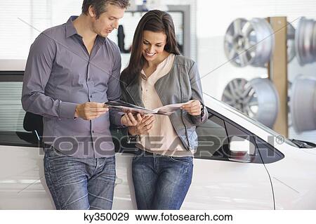 Couple looking at car catalog in showroom View Large Photo Image Stock Photo - Couple looking at car catalog in showroom. Fotosearch
