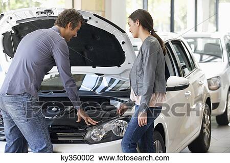 Couple looking at car engine in showroom View Large Photo Image Stock Image - Couple looking at car engine in showroom. Fotosearch