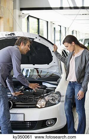 Couple looking at car engine in showroom View Large Photo Image Stock Image - Couple looking at car engine in showroom. Fotosearch