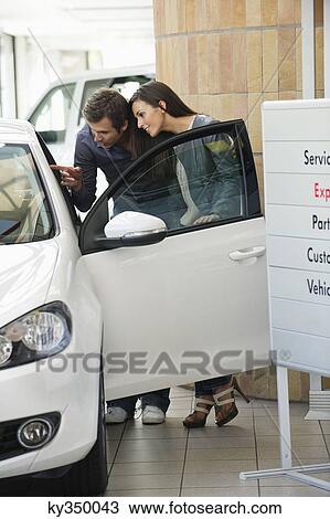 Couple looking inside car at showroom View Large Photo Image Stock Image - Couple looking inside car at showroom. Fotosearch
