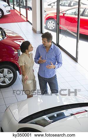 Female salesperson showing car to mid adult man in showroom View Large Photo Image Stock Image - Female salesperson showing car to mid adult man in showroom. Fotosearch