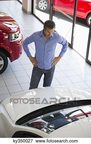 Mid adult man looking at a car in a showroom View Large Photo Image Stock Photo - Mid adult man looking at a car in a showroom. Fotosearch