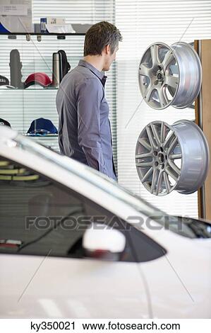 Mid adult man looking at hubcap in car showroom View Large Photo Image Stock Image - Mid adult man looking at hubcap in car showroom. Fotosearch