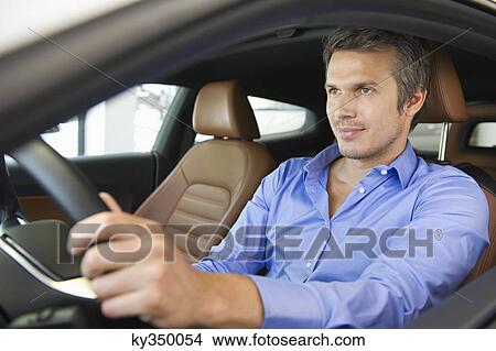 Mid adult man taking a test drive View Large Photo Image Picture - Mid adult man taking a test drive. Fotosearch