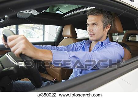 Stock Image - Mid adult man taking a test drive. Fotosearch