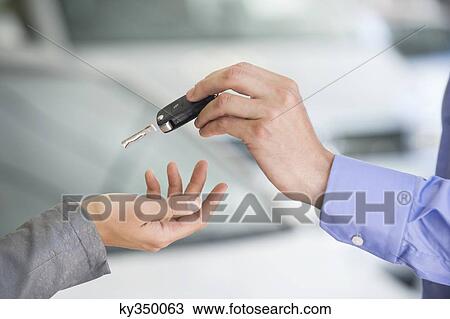 Stock Image - Salesman handing car key to woman. Fotosearch