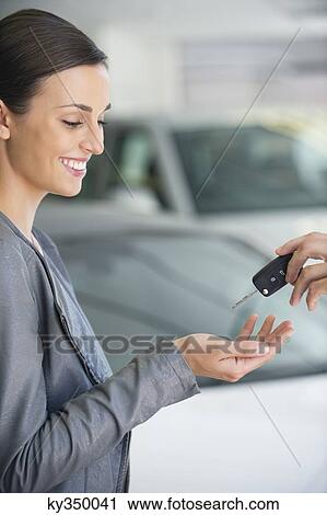 Side profile of a young woman taking car key in showroom View Large Photo Image Stock Image - Side profile of a young woman taking car key in showroom. Fotosearch
