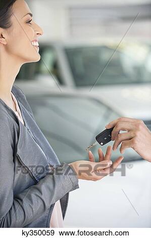 Side profile of a young woman taking car key in showroom View Large Photo Image Stock Photo - Side profile of a young woman taking car key in showroom. Fotosearch