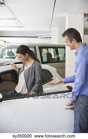 Young woman checking car from inside while man holding the door View Large Photo Image Stock Image - Young woman checking car from inside while man holding the door. Fotosearch