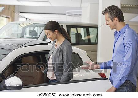 Young woman checking car from inside while man holding the door View Large Photo Image Stock Image - Young woman checking car from inside while man holding the door. Fotosearch