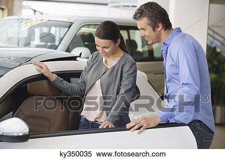 Young woman checking car from inside while man holding the door View Large Photo Image Stock Photography - Young woman checking car from inside while man holding the door. Fotosearch
