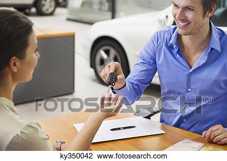 Young woman handing car key to a man View Large Photo Image Stock Image - Young woman handing car key to a man. Fotosearch