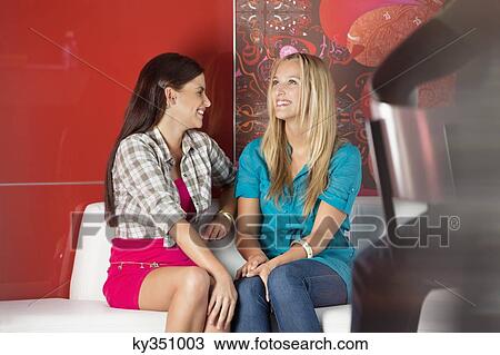 Female friends sitting on a sofa in a cafe View Large Photo Image Stock Image - Female friends sitting on a sofa in a cafe. Fotosearch