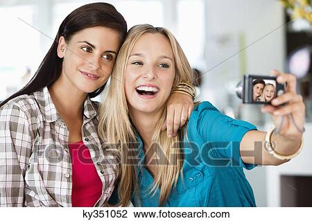 Female friends taking a picture of themselves with a camera View Large Photo Image Stock Image - Female friends taking a picture of themselves with a camera. Fotosearch