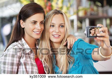 Female friends taking a picture of themselves with a camera View Large Photo Image Stock Photo - Female friends taking a picture of themselves with a camera. Fotosearch