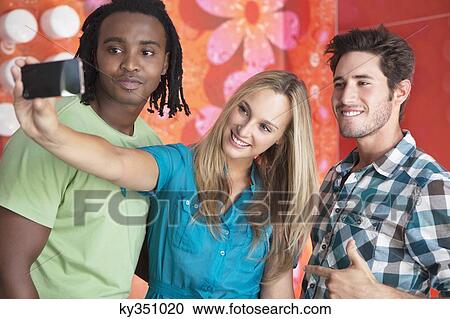 Friends taking a picture of themselves with a mobile phone View Large Photo Image Stock Image - Friends taking a picture of themselves with a mobile phone. Fotosearch