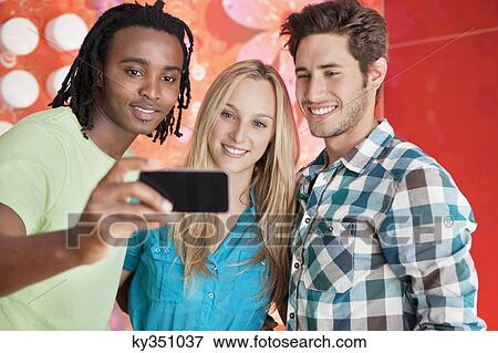 Friends taking a picture of themselves with a mobile phone View Large Photo Image Stock Photo - Friends taking a picture of themselves with a mobile phone. Fotosearch