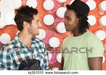 Stock Image - Friends talking at a cafe and smiling. Fotosearch