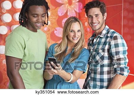 Picture - Friends text messaging on a mobile phone in a bar. Fotosearch