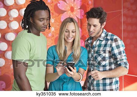 Friends text messaging on a mobile phone in a bar View Large Photo Image Stock Photography - Friends text messaging on a mobile phone in a bar. Fotosearch