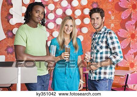 Stock Image - Portrait of friends having drinks at a bar. Fotosearch