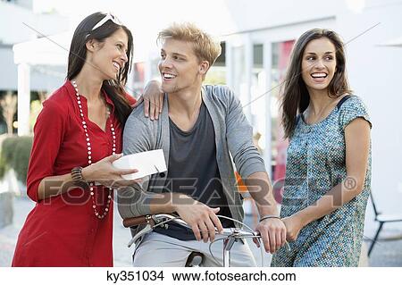 Smiling young man with two women cycling View Large Photo Image Picture - Smiling young man with two women cycling. Fotosearch