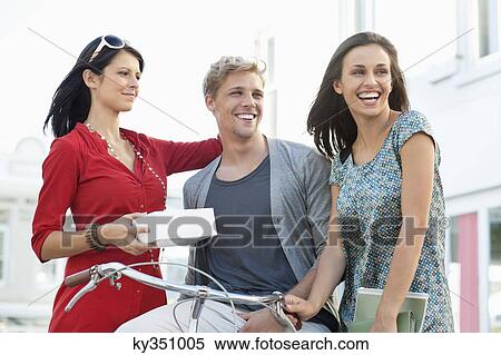 Smiling young man with two women cycling View Large Photo Image Stock Photography - Smiling young man with two women cycling. Fotosearch