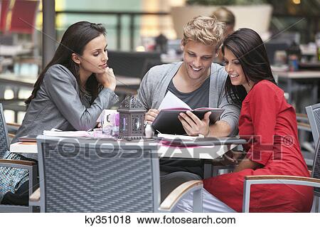 Young man with two young women looking at menu in a restaurant View Large Photo Image Stock Photo - Young man with two young women looking at menu in a restaurant. Fotosearch