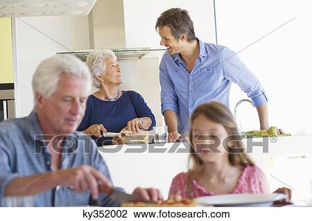 Man cutting cake with his granddaughter and his wife talking to her son in background View Large Photo Image Stock Image - Man cutting cake with his granddaughter and his wife talking to her son in background. Fotosearch