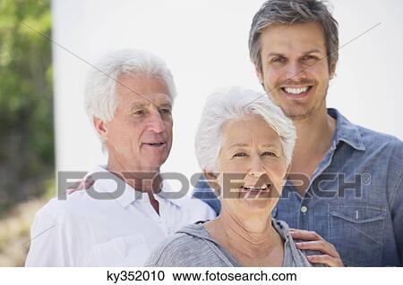 Stock Image - Mid adult man smiling with his parents. Fotosearch