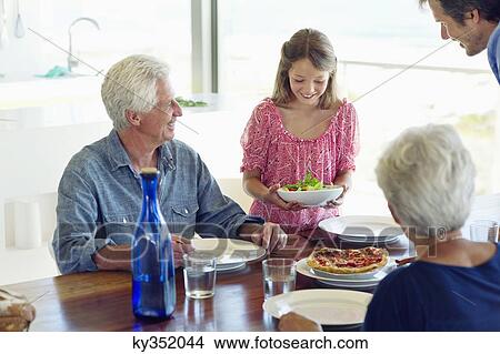 Multi generation family eating food at a dining table View Large Photo Image Picture - Multi generation family eating food at a dining table. Fotosearch