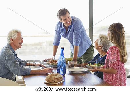 Multi generation family eating food at a dining table View Large Photo Image Stock Photo - Multi generation family eating food at a dining table. Fotosearch