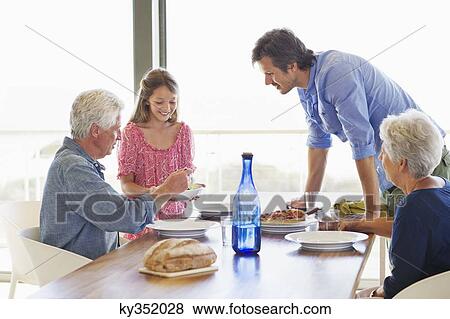 Multi generation family eating food at a dining table View Large Photo Image Stock Photo - Multi generation family eating food at a dining table. Fotosearch