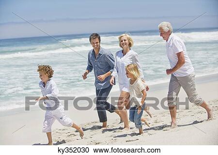 Stock Image - Multi generation family running on the beach. Fotosearch