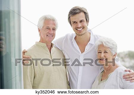 Portrait of a mid adult man standing with his arms around to his parents View Large Photo Image Stock Photograph - Portrait of a mid adult man standing with his arms around to his parents. Fotosearch