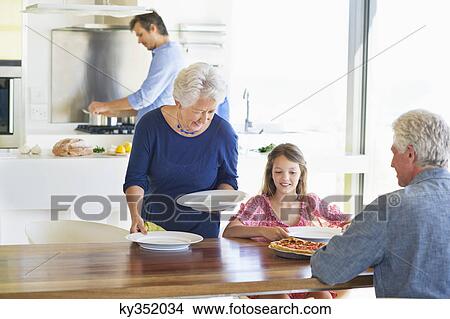 Senior woman placing plates on a dining table View Large Photo Image Picture - Senior woman placing plates on a dining table. Fotosearch