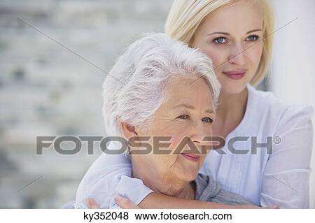 Young woman embracing her mother from behind View Large Photo Image Stock Photo - Young woman embracing her mother from behind. Fotosearch