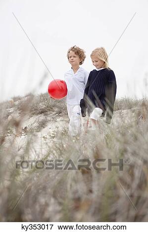 Boy and girl walking together against clear sky View Large Photo Image Stock Photo - Boy and girl walking together against clear sky. Fotosearch
