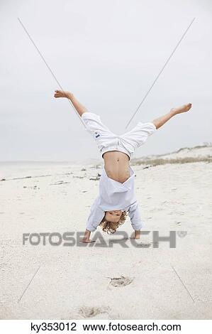 Boy doing handstand on beach View Large Photo Image Stock Image - Boy doing handstand on beach. Fotosearch