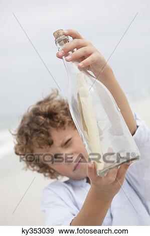 Boy looking at message in a bottle on beach View Large Photo Image Stock Photo - Boy looking at message in a bottle on beach. Fotosearch