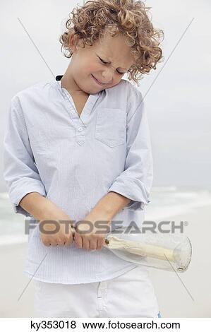 Boy pulling message from a bottle View Large Photo Image Stock Photo - Boy pulling message from a bottle. Fotosearch